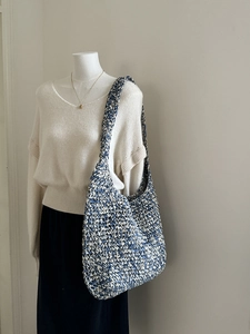 Detail of blue and white knitted hobo bag on mannequin showing texture and capacity