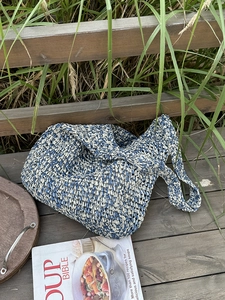 Close-up of blue and white straw woven beach bag on wooden floor with green grass