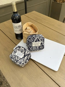 Detail of embroidered navy fabric coin pouch with white bird motifs on a wooden table