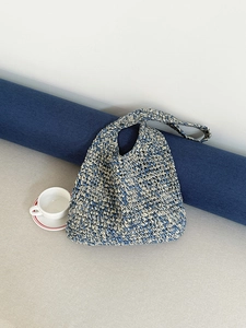 Detail of blue and beige woven straw beach bag featuring intricate handmade texture