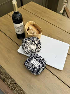 Detail of embroidered fabric pouches with geometric patterns on a wooden table