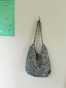 Detail of blue and beige woven shoulder bag showing soft cotton rope texture and patterns