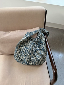 Detail of blue and white woven tote bag with wide strap on a soft beige chair
