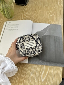Handheld view of embroidered mini cotton storage bag with fish and plant patterns