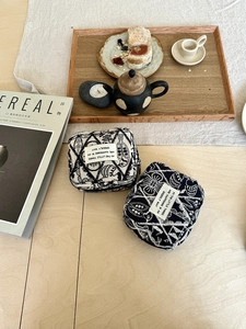 Close-up of dual-tone embroidered canvas storage pouches with geometric patterns on linen