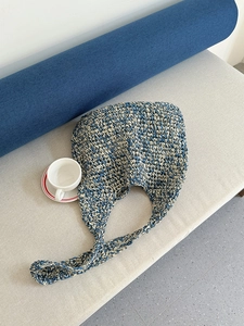 Detail of blue and beige woven straw tote bag resting on a casual terrace bench