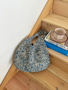Detailed knit texture of blue and white handmade straw beach bag on wooden stairs