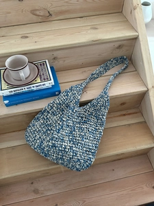 Close-up of blue and white handmade woven straw tote bag with soft hobo texture