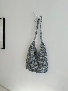 Detailed view of blue and white handmade woven straw tote bag with a long shoulder strap