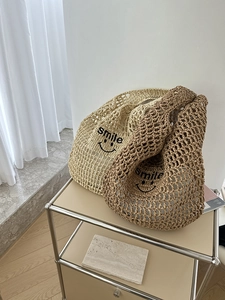 Detail of hollow woven straw tote bag with smile print in beige and brown colors