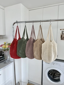 Detailed view of hollow knit cotton rope tote bags in five assorted colors on a hanger