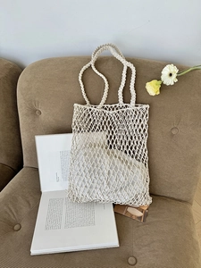 Nahaufnahme der weißen Baumwoll-Netztasche mit Rautenmuster auf einem Samtsofa