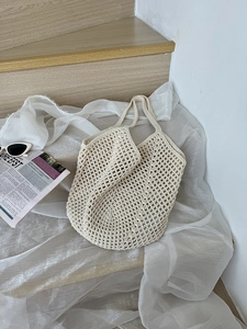 Detail of a beige crochet tote bag with hollow mesh design and natural cotton texture