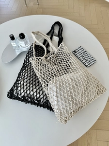 Flachbild von handgewebten Netztaschen in Schwarz und Creme auf einem weißen Tisch