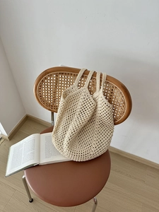 Detail of hollow woven cotton rope tote bag in cream white on a vintage chair