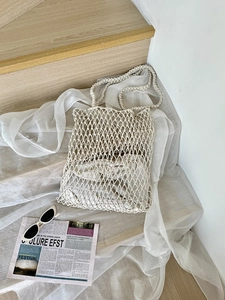Handgewebte beige Häkeltasche mit hohlem Rautennetz auf rustikalem Holzhintergrund