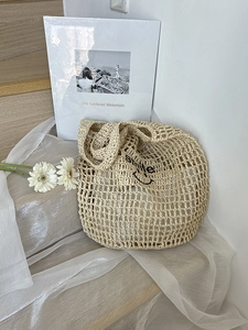 Detail of hand-woven mesh beach bag with black Smile embroidery and beige knit texture