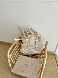Detail einer gewebten Netztasche mit Innentasche aus Stoff auf einem Rattanstuhl