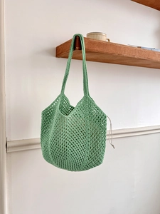 Detail of light green hollow cotton mesh bag with a white drawstring closure and soft texture