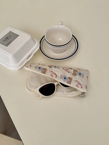 Cute canvas pouch with poodle print and cat eye sunglasses on a cream background