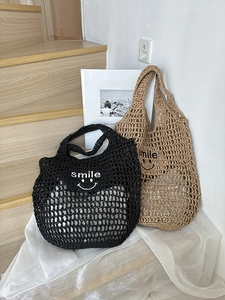 Close-up of hollow out straw bags in black and tan with smile embroidery and mesh pattern