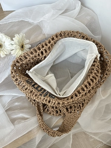 Handwoven straw tote bag with cutout design and internal drawstring pouch for beach