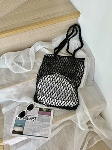 Detail einer schwarzen Häkel-Netztasche mit weißem Innenfutter auf einer Holztreppe