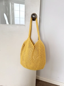Detail of yellow crochet tote bag showing openwork cotton rope weaving and hollow texture