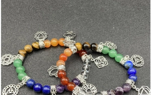 Close-up of natural chakra stone bracelets with silver yoga pendants and energy beads