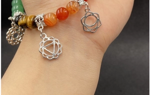 Detail of seven chakra bead bracelet with natural gemstones and silver pendants on wrist