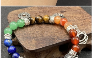 Macro detail of natural crystal chakra bracelet with colorful stones and silver wheel charm