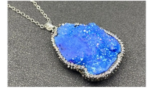 Vue macro d'un pendentif en cristal druzy bleu avec bordure en strass et chaîne argent