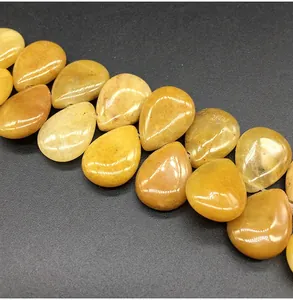 Macro shot of polished teardrop yellow jade beads with natural textures on black surface
