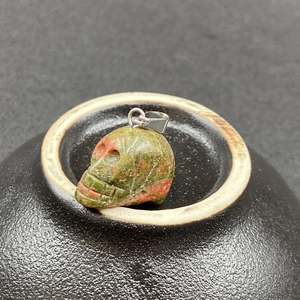 Vue macro d'un pendentif crâne en unakite sculpté à la main avec fermoir en métal argenté