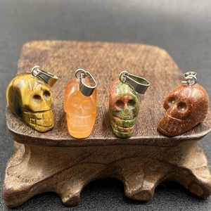 Vue détaillée de pendentifs crâne en œil de tigre et agate sur un support en bois