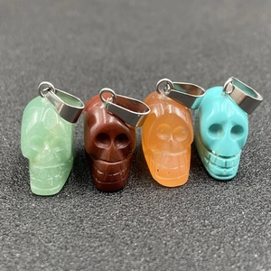 Vue détaillée de quatre pendentifs crânes en pierre de différentes couleurs avec attaches