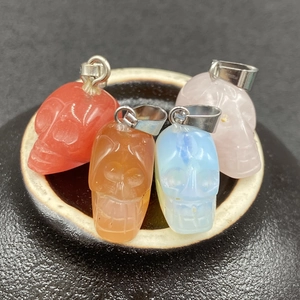 Vue macro de quatre pendentifs crâne en pierre précieuse colorée sur un bol en céramique