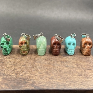 Vue détaillée de divers pendentifs crânes en pierres fines sur un socle en bois