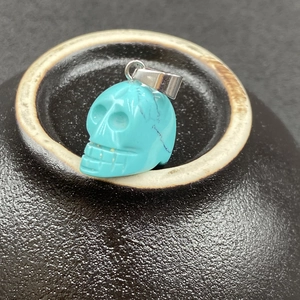 Vue rapprochée d'un pendentif crâne turquoise avec veines noires sur poterie sombre