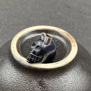 Vue détaillée d'un pendentif crâne en grès bleu avec fermoir métallique sur céramique