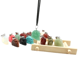 Pendentifs crâne en cristal d'oeil de tigre et agate sur un petit support en bois