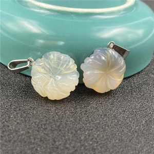 Macro shot of carved agate flower pendants with silver metal clasps on a ceramic bowl