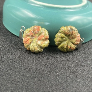 Macro shot of two carved unakite flower pendants with silver bails on a textured background