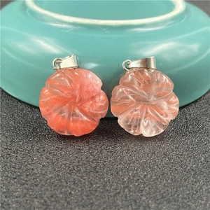 Macro shot of two strawberry quartz flower pendants with silver clasps on black surface