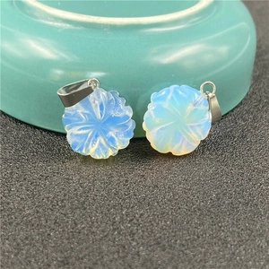 Macro detail of two blue opal carved flower pendants with silver bails on green porcelain