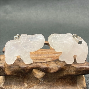 Vue détaillée de deux pendentifs éléphants en cristal translucide sur socle en bois