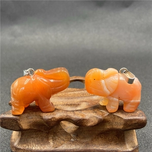 Gros plan de deux pendentifs en forme d'éléphant sculptés dans de la cornaline orange