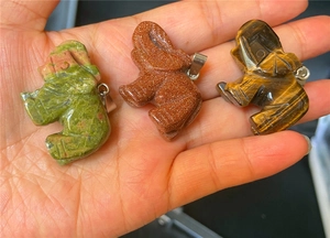 Détail des pendentifs éléphants sculptés en aventurine et œil de tigre naturel