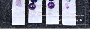 Makro-Detail von drahtumwickelten Selenitstäben mit bunten Chakra-Kristallsteinen