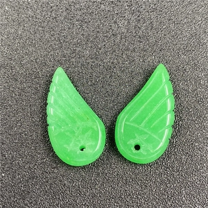 Macro view of green angel wing pendants with detailed feather texture and hole